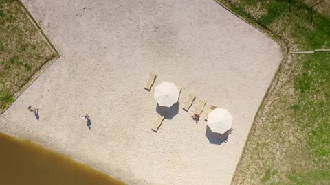 People taking rest at the beach area with sand and loungers near a small lake Stock Footage 148736218