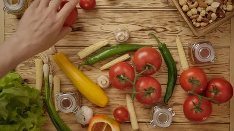 People taking vegetables and another ingredients from table Stock Footage 119970603