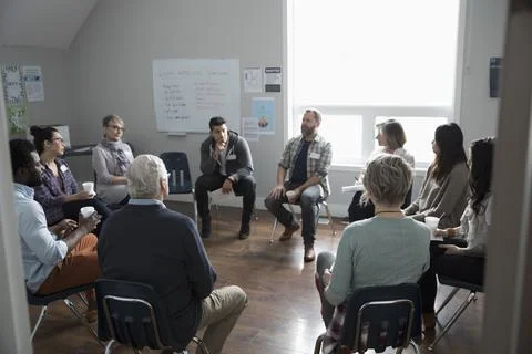 People talking in circle at support group in community center Stock Photos