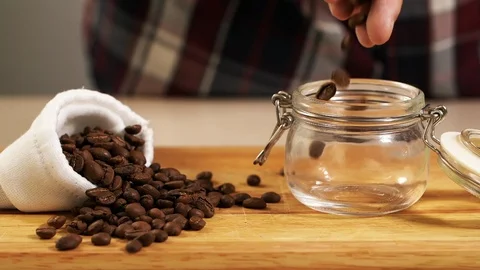 People throw roast coffee bean in jar slowmotion closeup, fill container arabica Stock Footage 113076200
