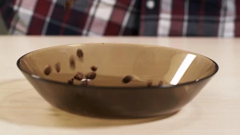 People throws falling roasted coffee beans into a plate on the table close-up 4K Stock Footage 113059640