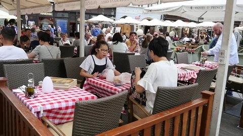 People tourists in Prague sit eat and drink communicate at street restaurant Stock Footage