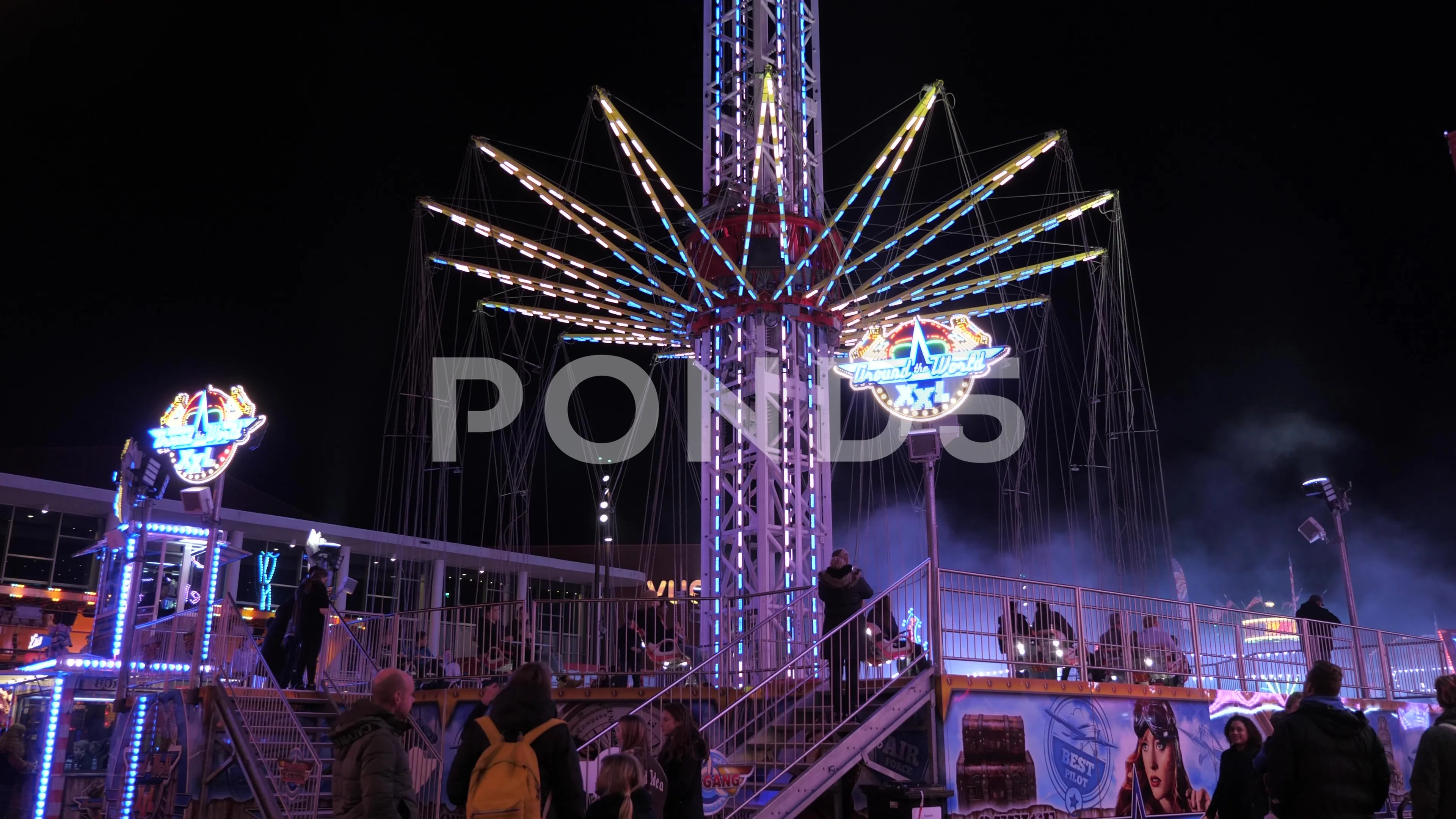People On Tower Swinger Ride In Amusement Park at night at anual funfair