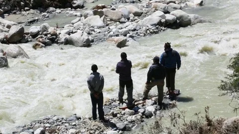 People trying to cross the harsh stream with the help of rope Stock Footage 77450116