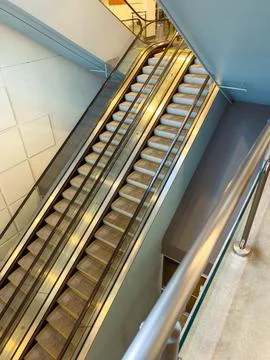 People use an escalator to move between floors in a modern building during .. Stock Photos
