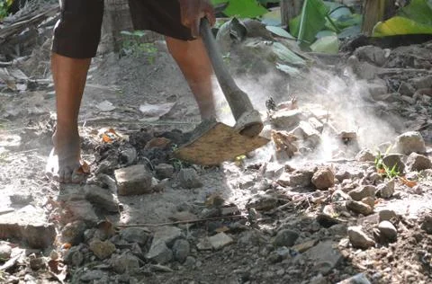 People using a hoe to level the ground and dusty stones in the garden Stock Photos