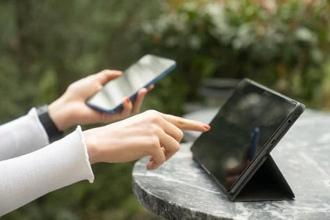 People Using Smartphone and Tablet Together at Outdoor Cafe 库存照片