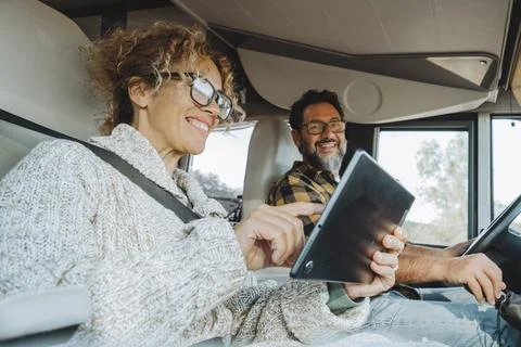 People using tablet device during travel vacation inside camper van. Techno.. Stock Photos