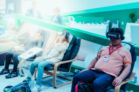 People with VR goggles on comfortable sofas Stock Photos