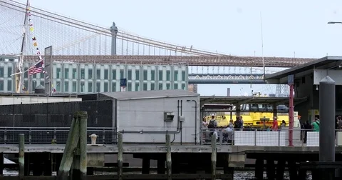People wait in line on the Pier 11 Ferry Terminal in Manhattan as boat pass by Stock Footage 77734447
