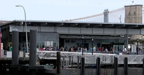 People wait in line on the Pier 11 Ferry Terminal in Manhattan tugboat pass by Vídeo Stock 77936848
