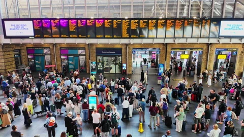 People waiting and checking the large train schedule screen at King's Cross Stock Footage 341300513