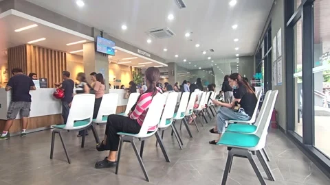 People waiting and lining up at a modern hospital reception area. Patients Stock Footage 317749066
