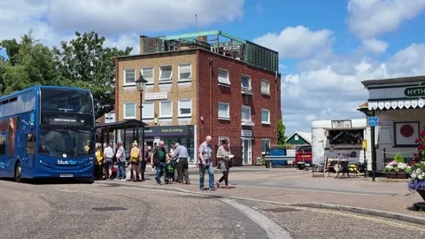 People waiting at a bus stop next to a blue double-decker bus Stock Footage 340107972