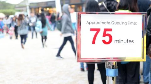 People waiting in a long queue, focus on the information sign. Stockfoto's