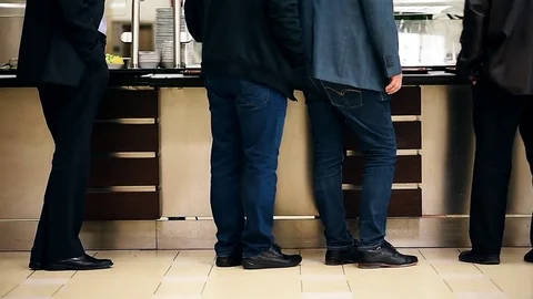 People waiting in a row inside a canteen Видео 75711937