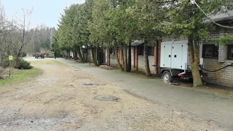 People walk along a path beside buildings and trees in a quiet area during the m Stock-Footage 330188438