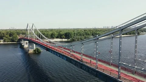 People walk and ride their bicycles on the pedestrian bridge over the river. Stock Footage 140989341
