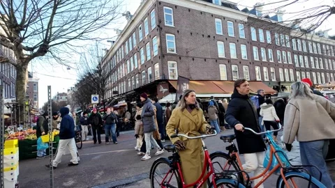People walk down Albert Cuypmarkt in Amsterdam street market on a cloudy wi.. Video stock 334061870