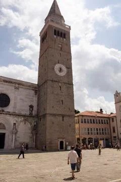 People walk in front of clock tower of Assumption Cathedral Stock Photos