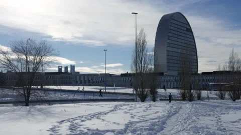 People walk outside in the snow close to the BBVA headquarters in Las Tablas Stock Footage 146333046