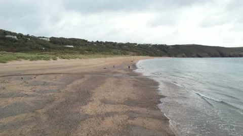 People walk on sandy peach between landscape and sea Video stock 185922495