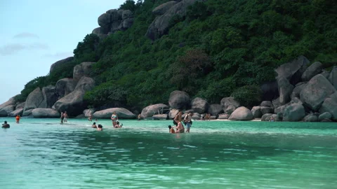 People walk on a slightly flooded thin sandy strip between two islands in thai Stock Footage 236247909