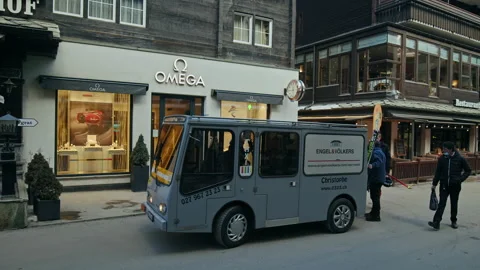 People walk in the streets of Zermatt by OMEGA luxury watch brand Shop. Stock Footage