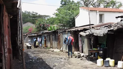 People walk through the mud covered streets of Kibera, Kenya. Stock-Footage 129199342
