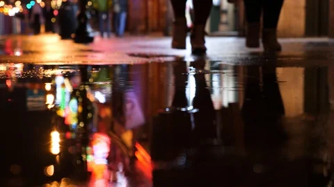 People walk through puddle in night city, lighten by neon signs. Stock Footage 121290616