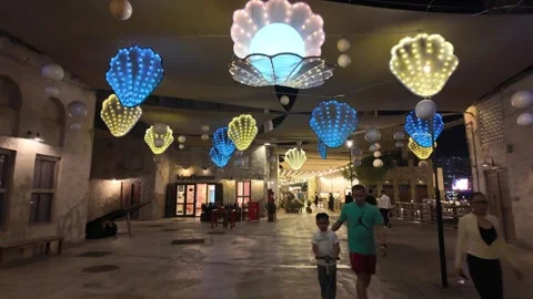 People walk through Souk Al Seef at night along the historic Dubai Creek. Stockbeeldmateriaal 332231874