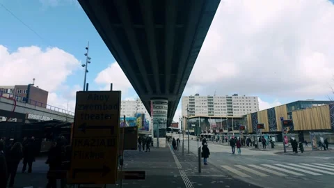 People walk under a massive concrete overpass structure in an urban area of Stock Footage 333813464