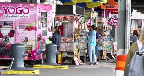 People walk by while customers buy food from street vendor’s carts in Manhattan Video stock 77519434