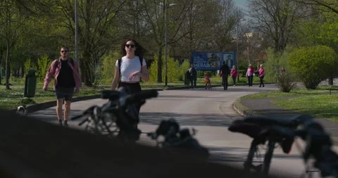 People walking along paved path with bicycles in foreground 스톡 동영상 332550113