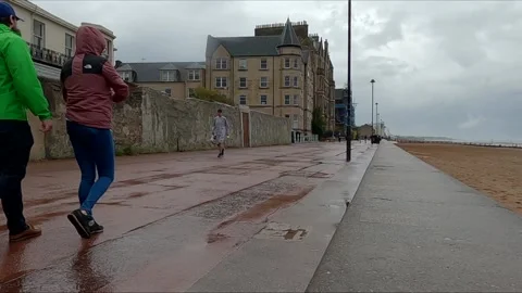 People walking along promenade in the rain Portobello Edinburgh Scotland Stock Footage