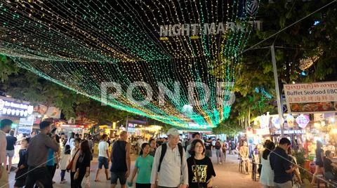 People walking along a tourist street lit by lights Stock Photos