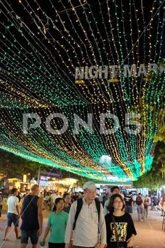 People walking along a tourist street lit by lights Stock Photos