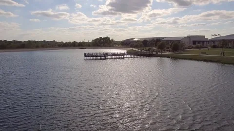 People Walking Alongside Lake With Dock Bridge Drone Hover Over Water Stock Footage 76380396