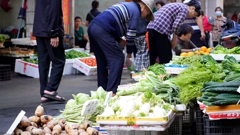 People walking and choosing vegetables in a farmer's market in China Stock Footage 334099059
