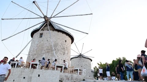 People walking and exploring windmill in Alacati town Stock Footage 84136819