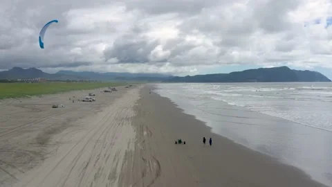 People walking and having fun and a good time at the beach during a cloudy day Vídeo Stock 218348557