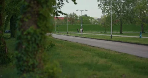 People walking and roller skating along path at Jarun Lake Stock Footage 332948658