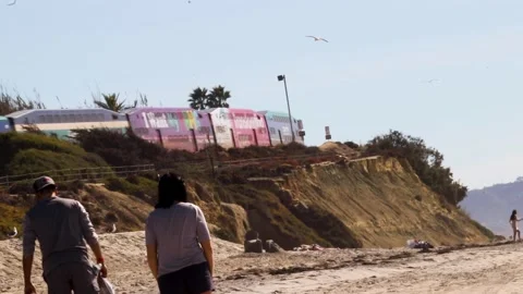 People walking on the beach with coaster train passing by Stock Footage 221381278