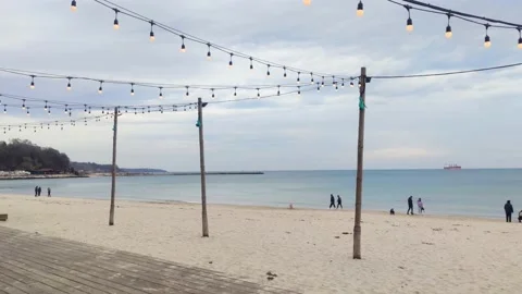 People walking on the beach in a cold cloudy day Stock Footage 233463190