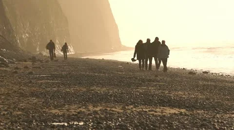 People walking on beach at sunset Stock Footage 10843959