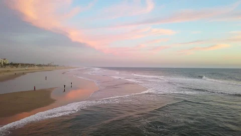 People walking on the beach as the surf rolls in. Huntington Beach California Stock Footage 127593215