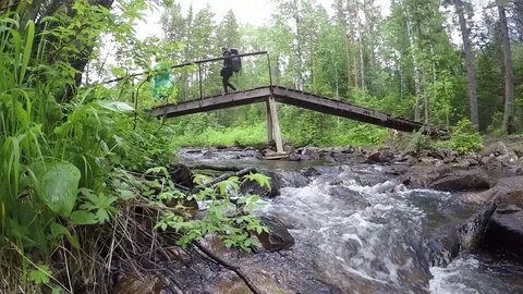 People walking on bridge over mountain river Stock Footage 79684047