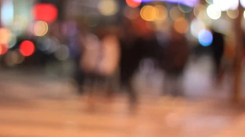 People walking cross busy street intersection at night defocused Stock Footage