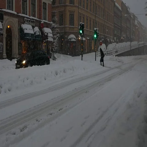People walking to cross intersection and cars moving in streets, heavy snowy day Video stock 69553712