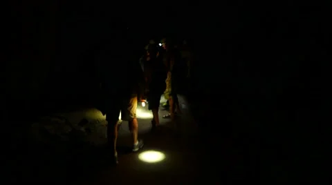 People walking in dark cave flashlight spot on the floor and wall Stock Footage 50571912
